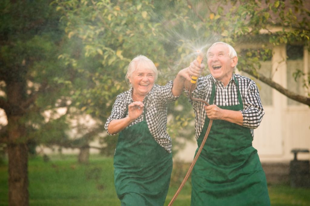 elderly couple playing with water hose