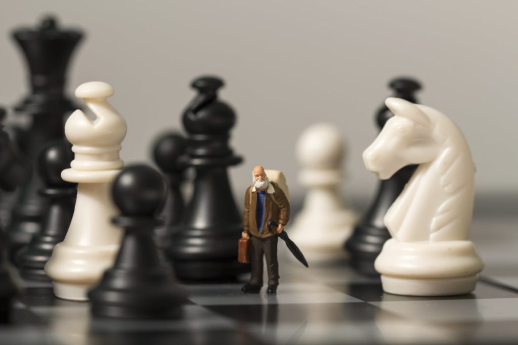 man figurine standing on chess board