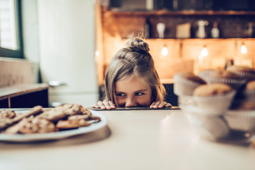 girl eyeing a plate of cookies